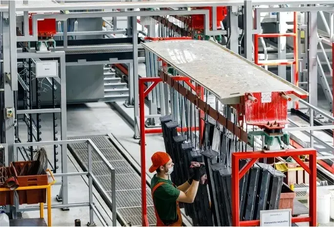 zdjęcie człowieka przy elementach po galwanizeri Zdjęcie przedstawiające dwie linie galwanizeri w zakładzie Strumet
